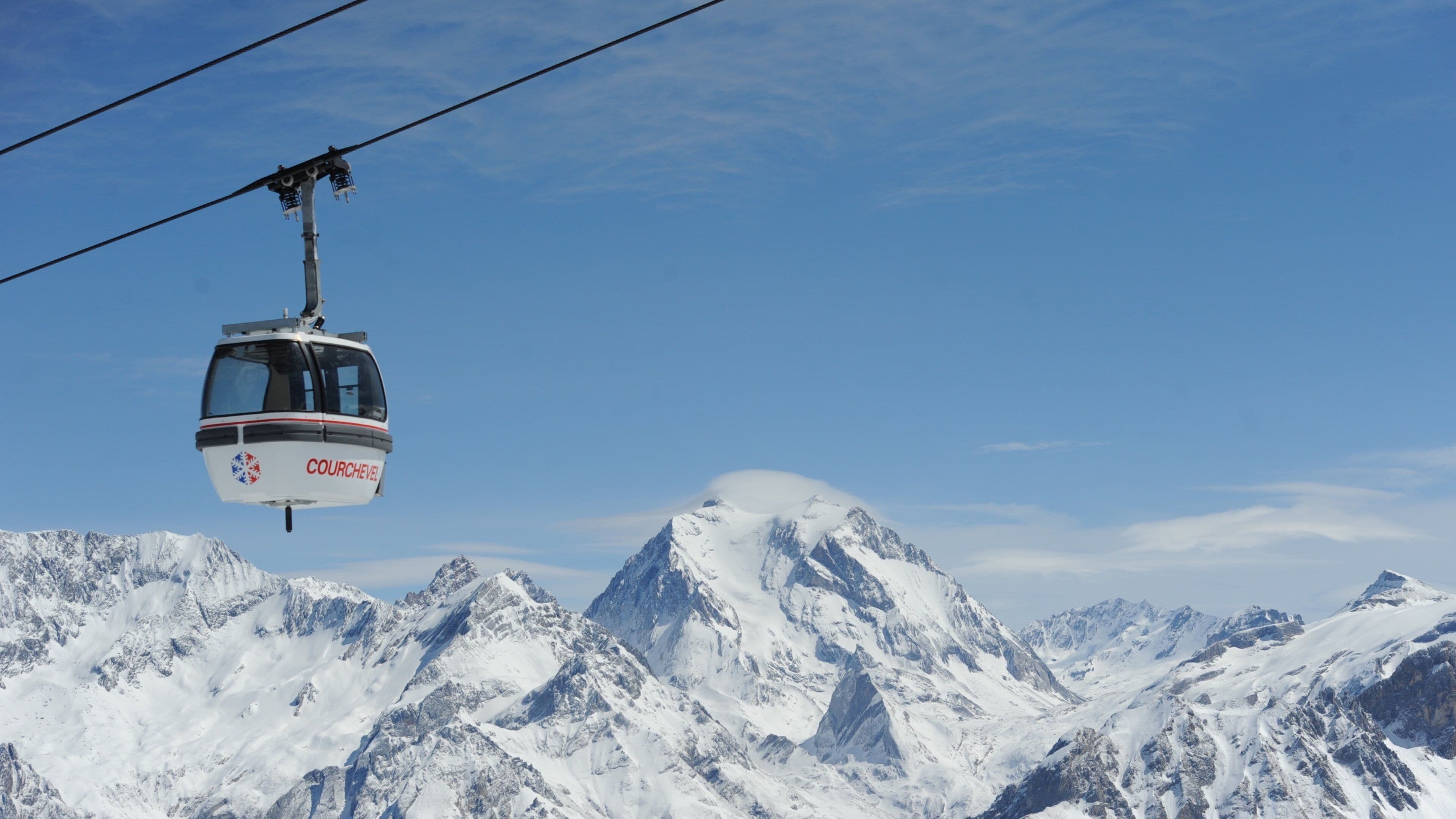 A cable car labeled "COURCHEVEL" suspended over snow-covered mountains.