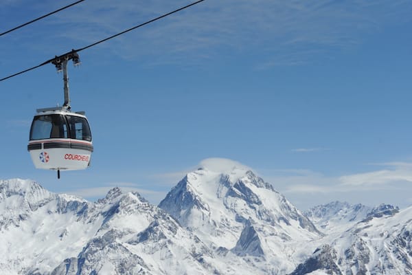 Une télécabine portant l’inscription « COURCHEVEL » est suspendue au-dessus de montagnes enneigées.
