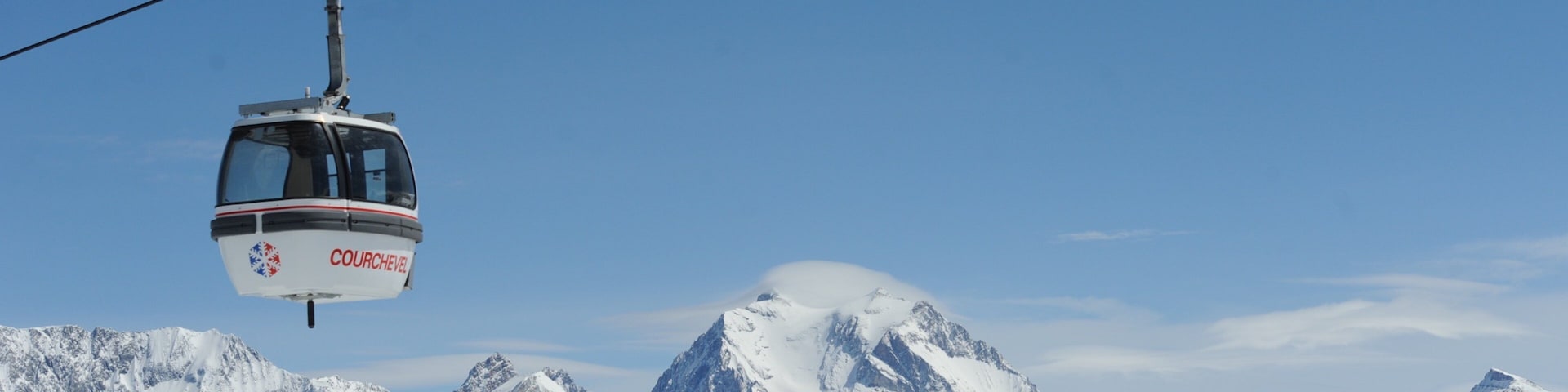 A cable car labeled "COURCHEVEL" suspended over snow-covered mountains.