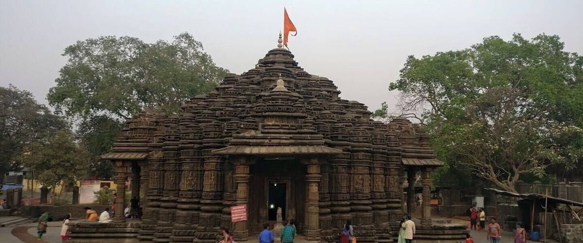 A stone temple with intricate carvings and a flag on top.