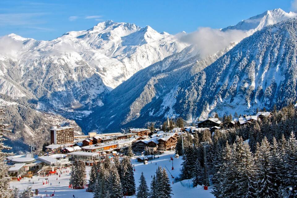 Une station de montagne enneigée, dotée de pistes de ski, de bâtiments d’hébergement et d’un télésiège.