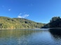 Ein ruhiger See, umgeben von dichtem Wald und Hügeln.