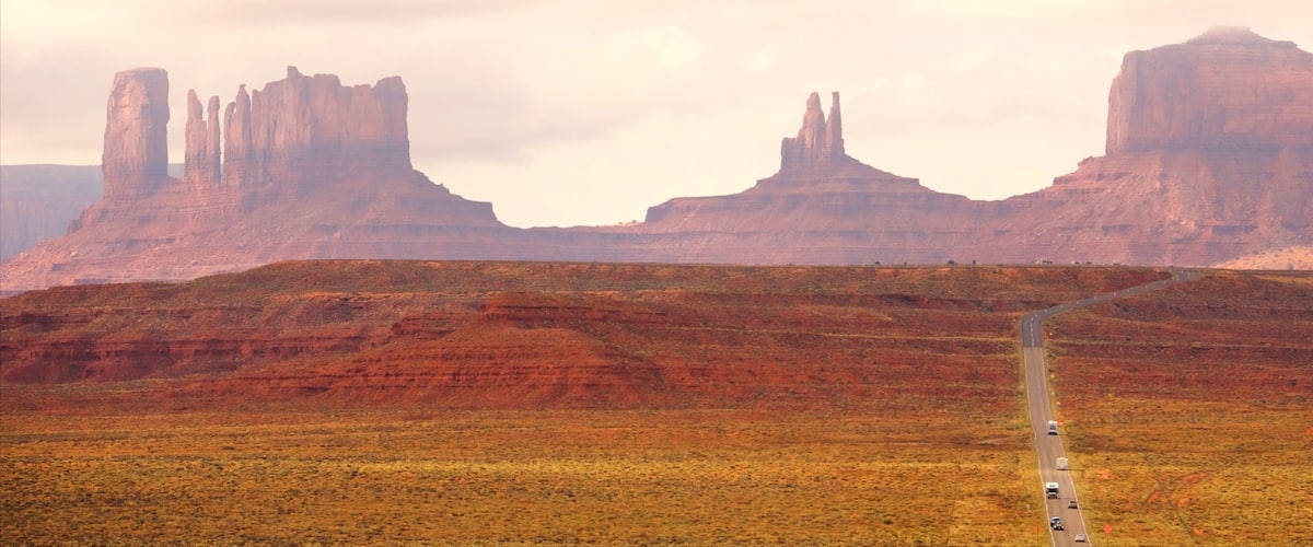 A road leading through a desert landscape with prominent rock formations.