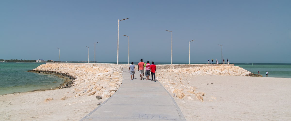 Budaiya which includes a beach and general coastal views as well as a small group of people