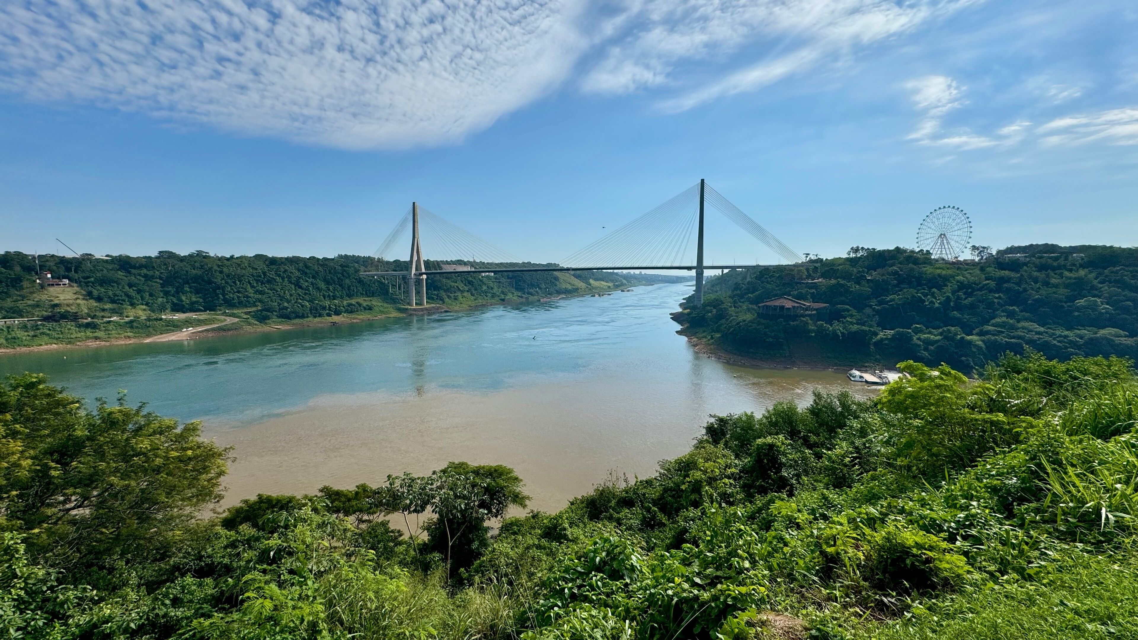 A river with a bridge and a Ferris wheel in the background.