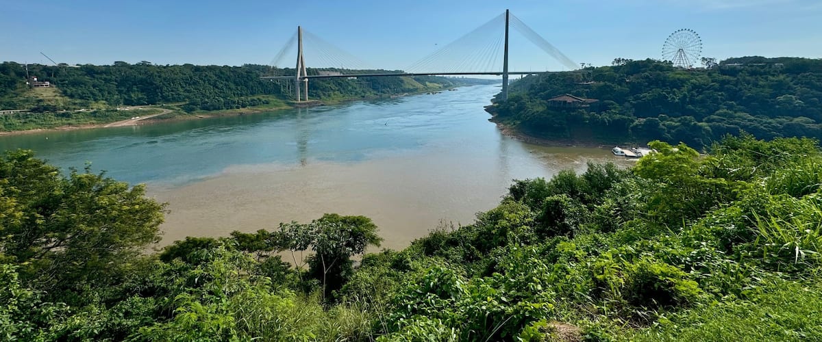 A river with a bridge and a Ferris wheel in the background.
