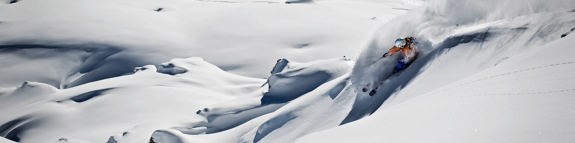 Um esquiador descendo uma encosta íngreme coberta de neve.