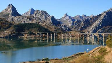 A mountain landscape with a bridge over a calm lake.