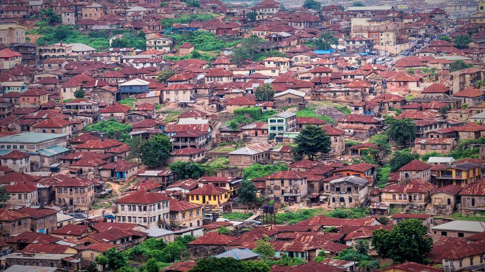 A densely packed urban area with numerous buildings, some with rusted roofs, and scattered greenery.