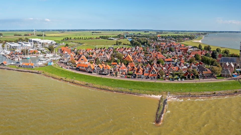 A coastal town with a marina, houses, and a lighthouse.