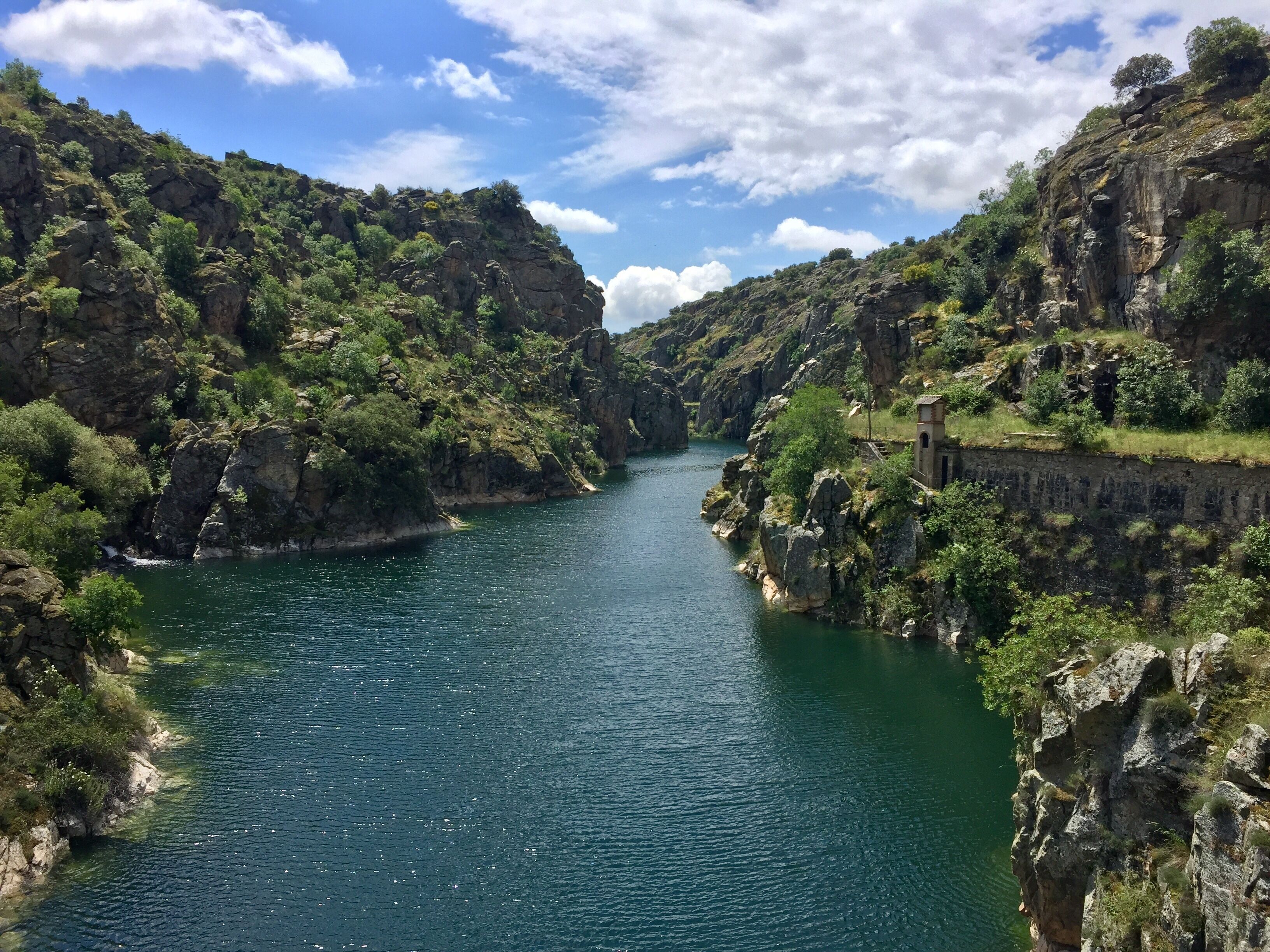 A river flanked by rocky cliffs and lush greenery.