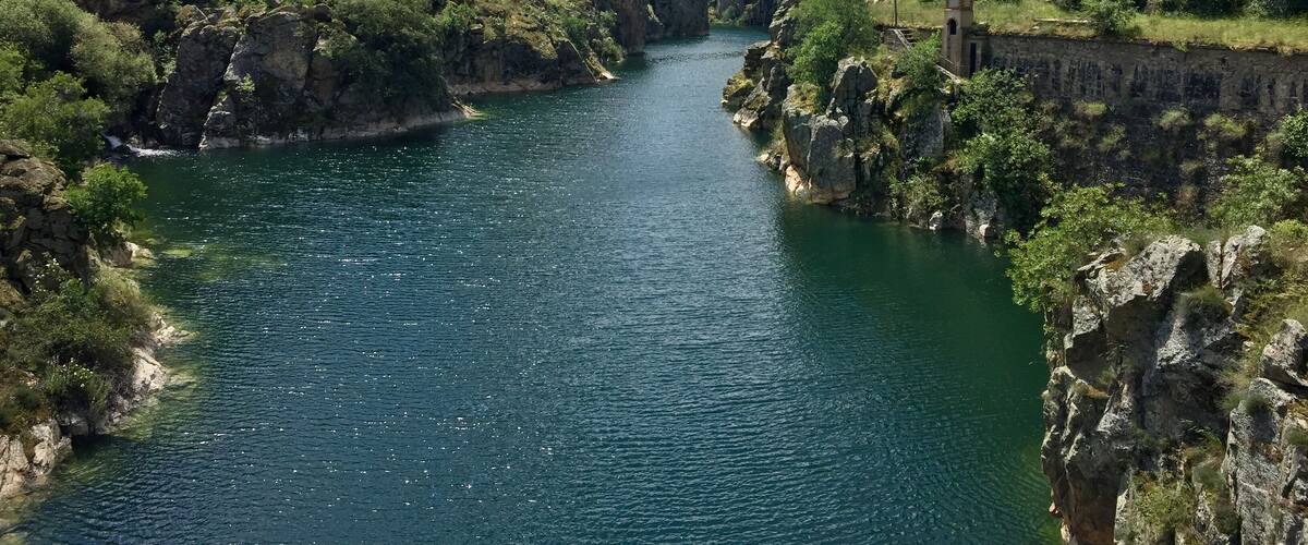 A river flanked by rocky cliffs and lush greenery.
