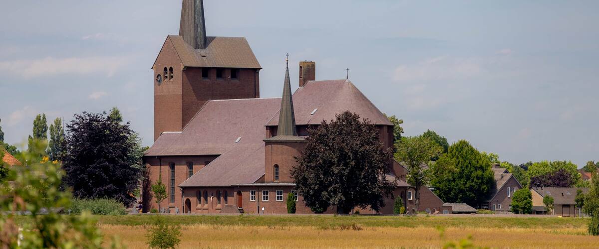 A church with a tall steeple and a brick building in a rural setting.