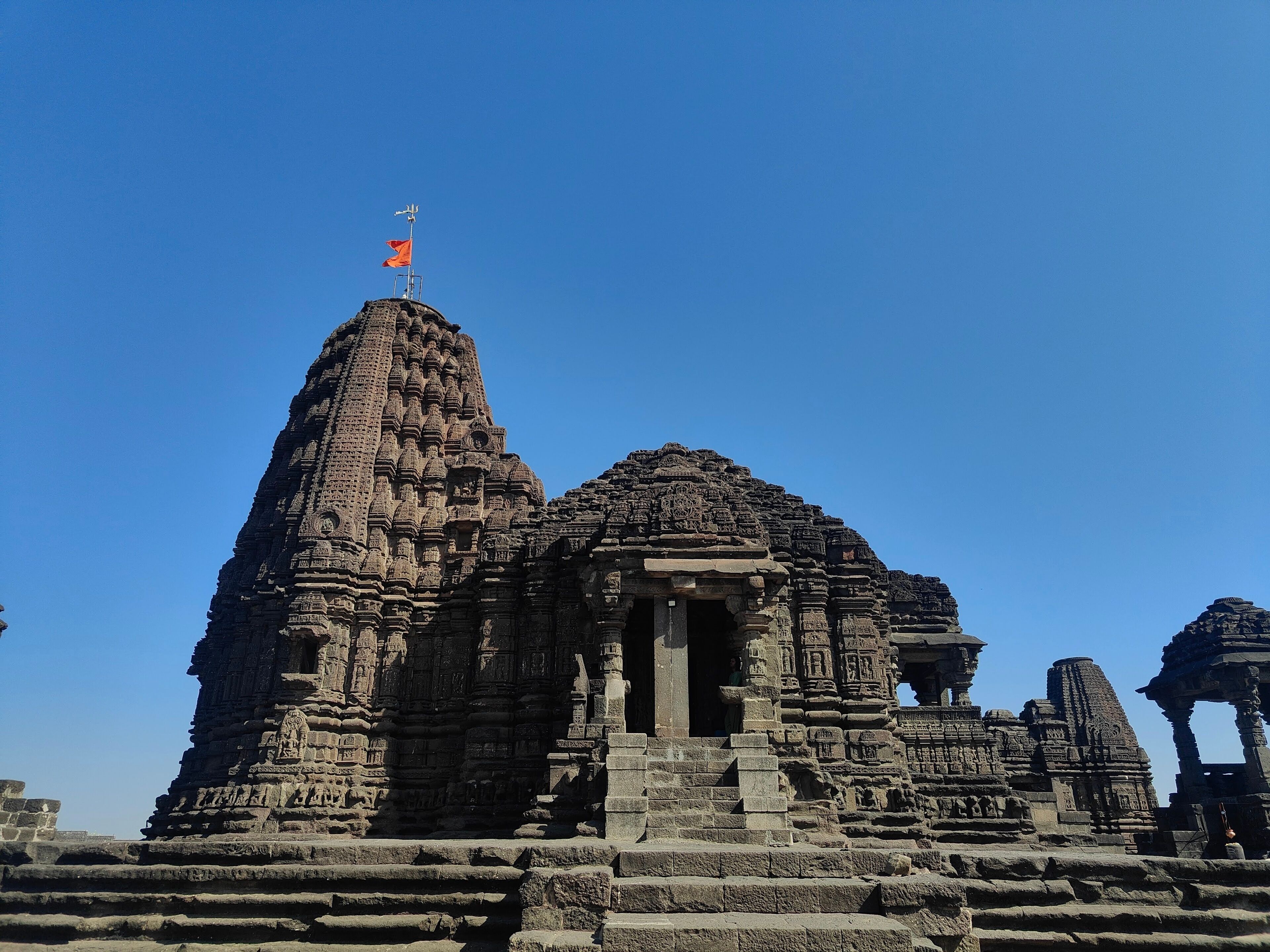 An ancient temple with intricate carvings and a flag on top.