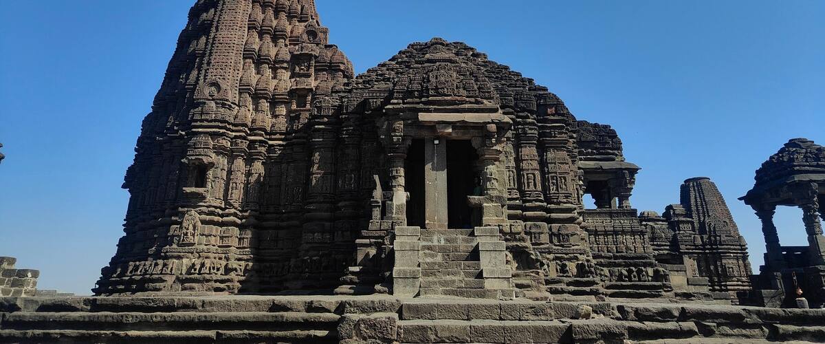 An ancient temple with intricate carvings and a flag on top.