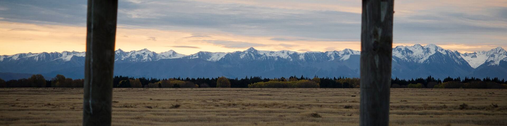 A metal gate in a field with a mountain range in the background.