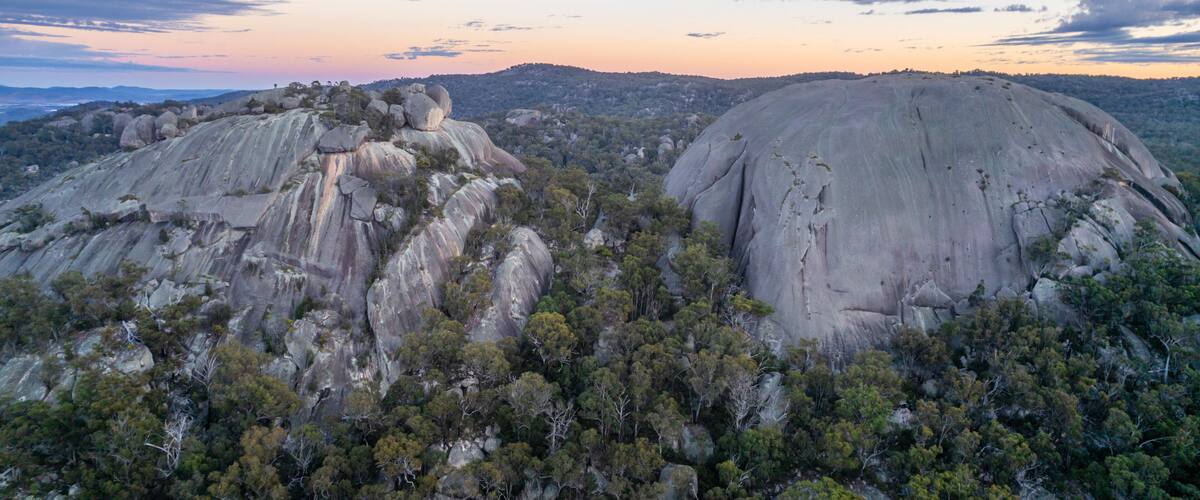 A landscape with two large rock formations surrounded by dense forest.
