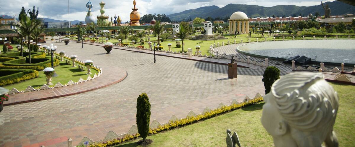 A landscaped park with a fountain, statues, and domed structures.