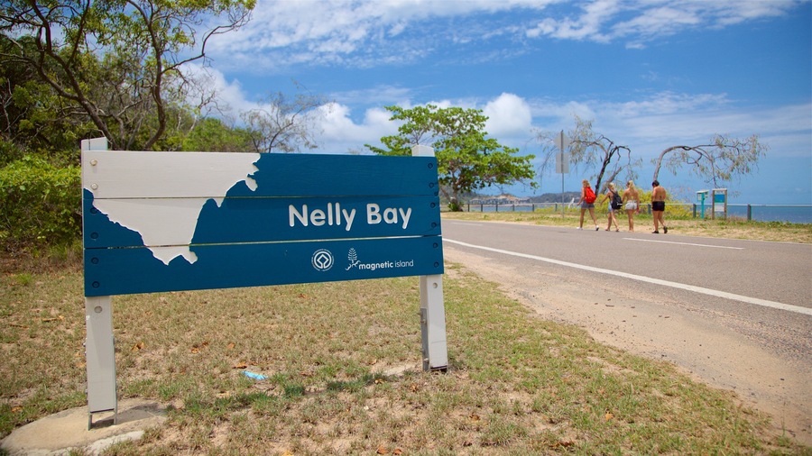 Señal de Nelly Bay con un paisaje costero al fondo.