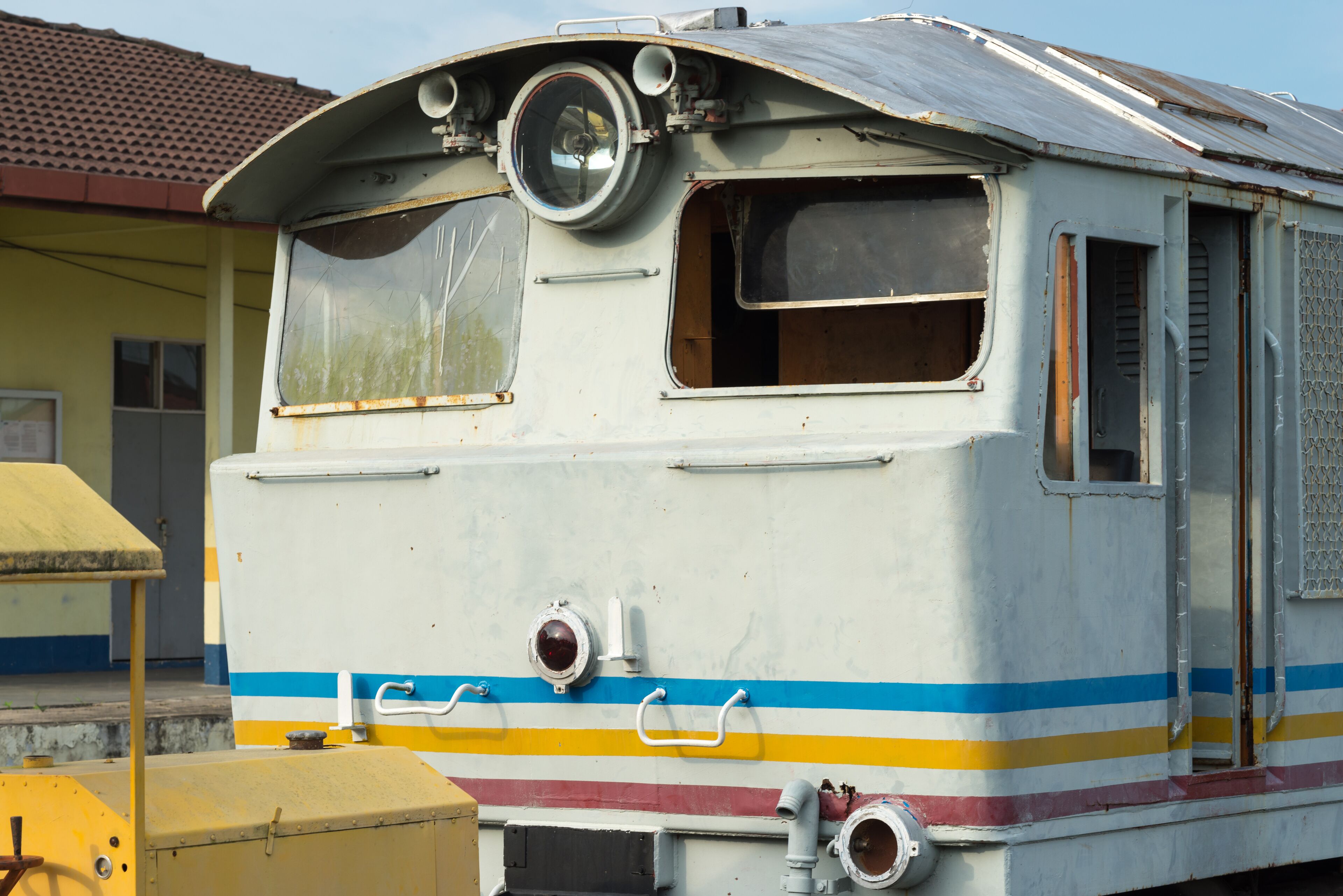 A vintage train with a curved roof, large windows, and a colorful stripe design.