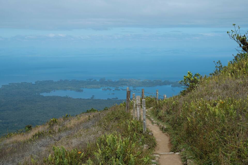 A dirt path leading to a coastal area with a view of the ocean and islands in the distance.