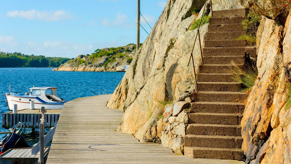 A wooden pier leading to a rocky staircase by the sea.