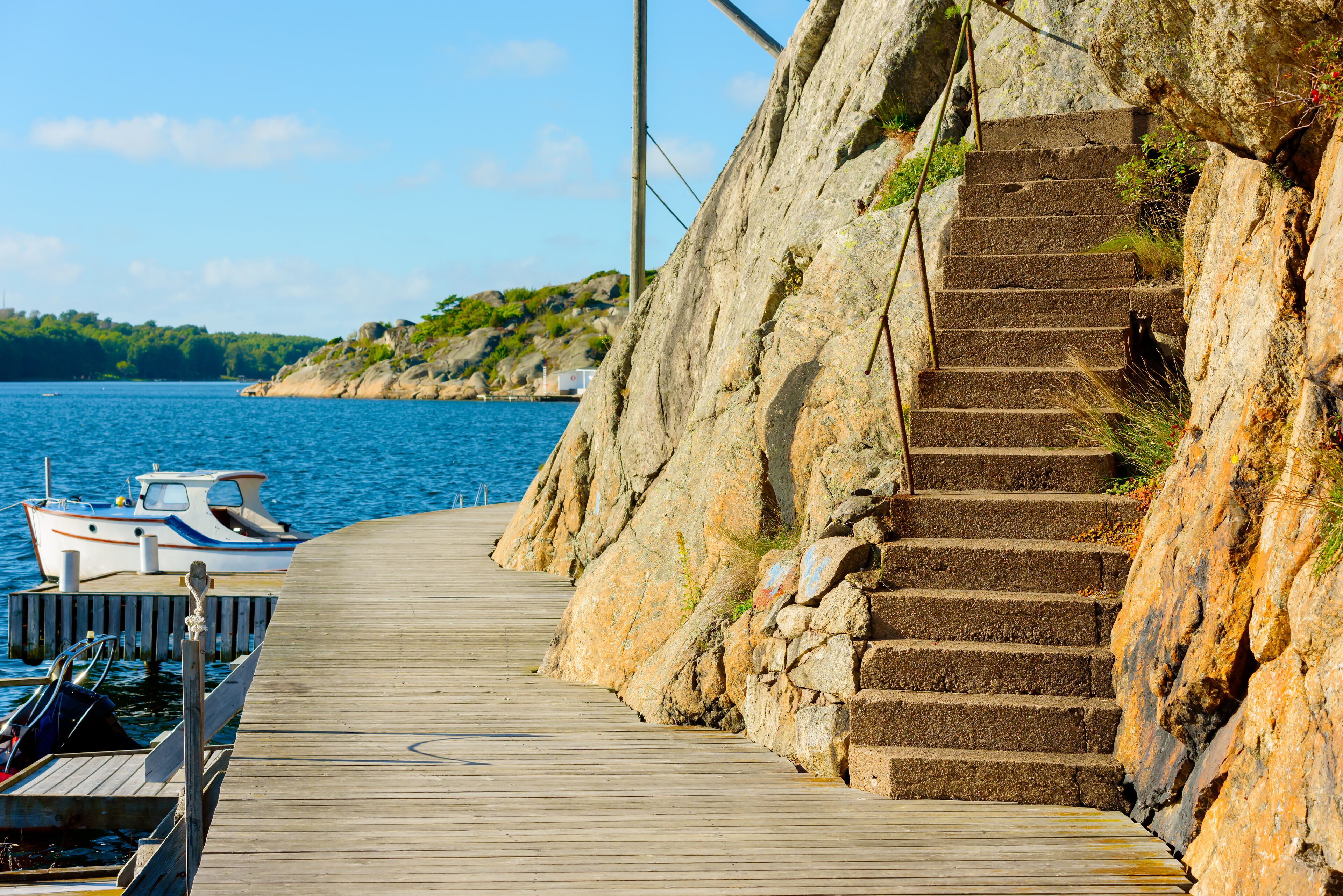 A wooden pier leading to a rocky staircase by the sea.