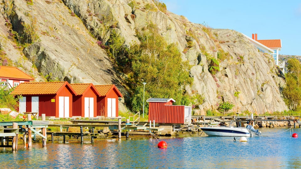 A coastal scene with red buildings, a dock, and a boat.