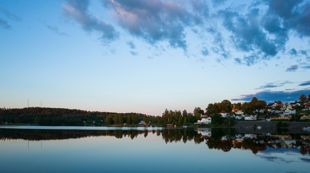 Bengtsfors city by the Lelång lake at Swedish summer night, Nordic town reflecting in calm water at blue hour, Sweden