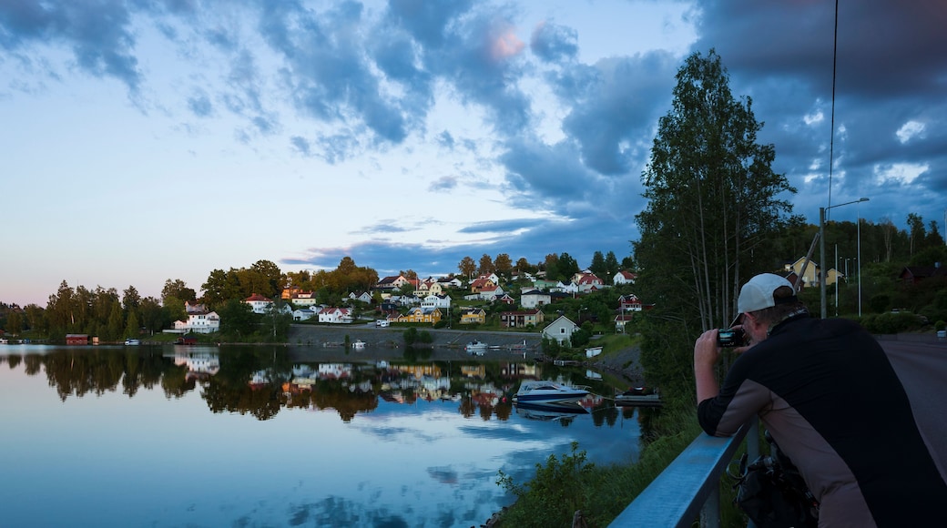 Bengtsfors city by the Lelång lake at Swedish summer night, Man is photographing city view reflecting in calm water, Sweden