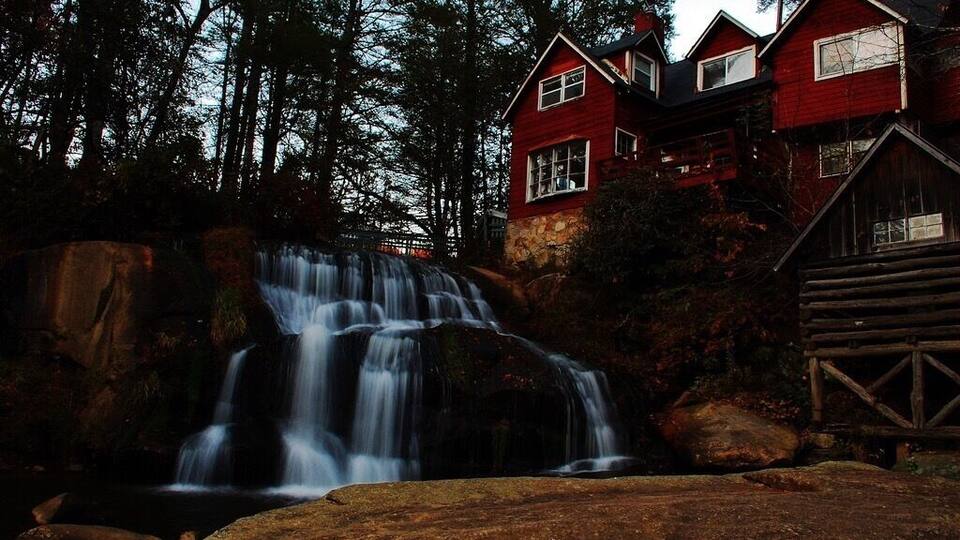 A red house with a waterfall in front.