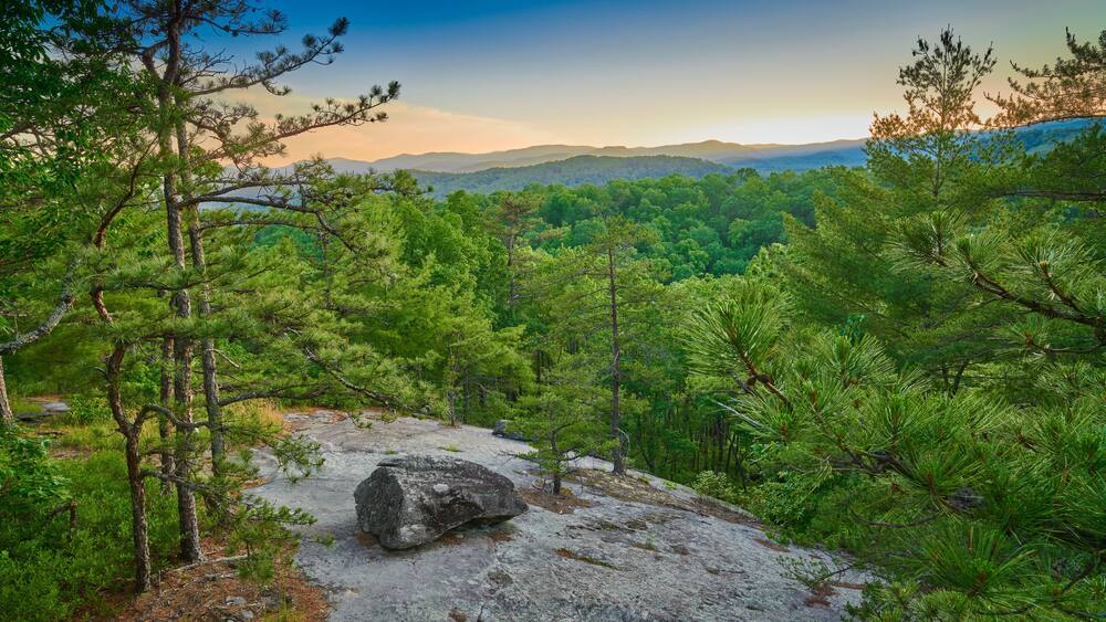 Exposed rock face with large boulder at sunset.