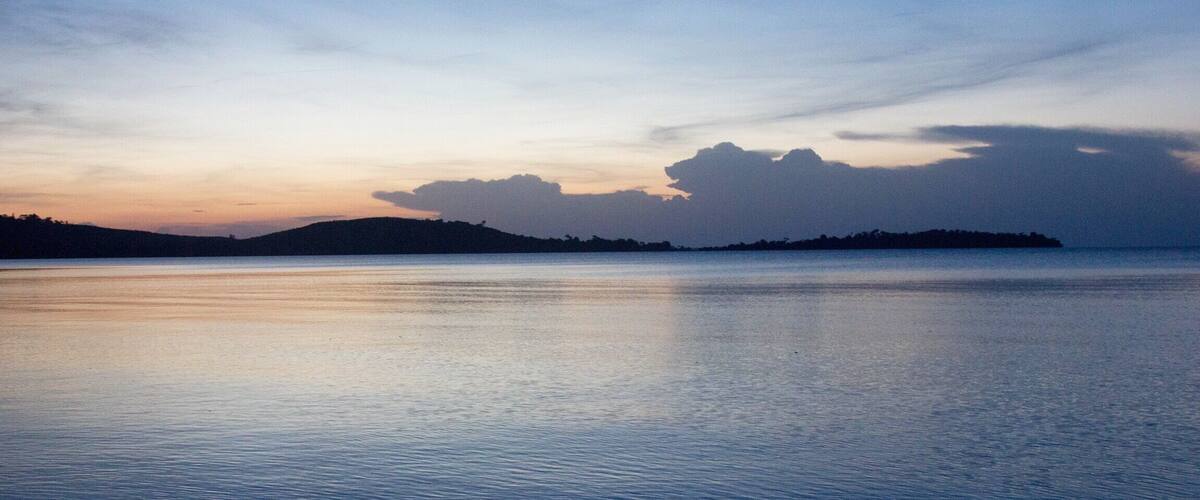 A calm body of water with a distant shoreline and a clear sky.