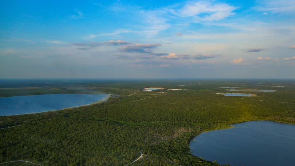 A vast forested landscape with multiple lakes and a clear sky.