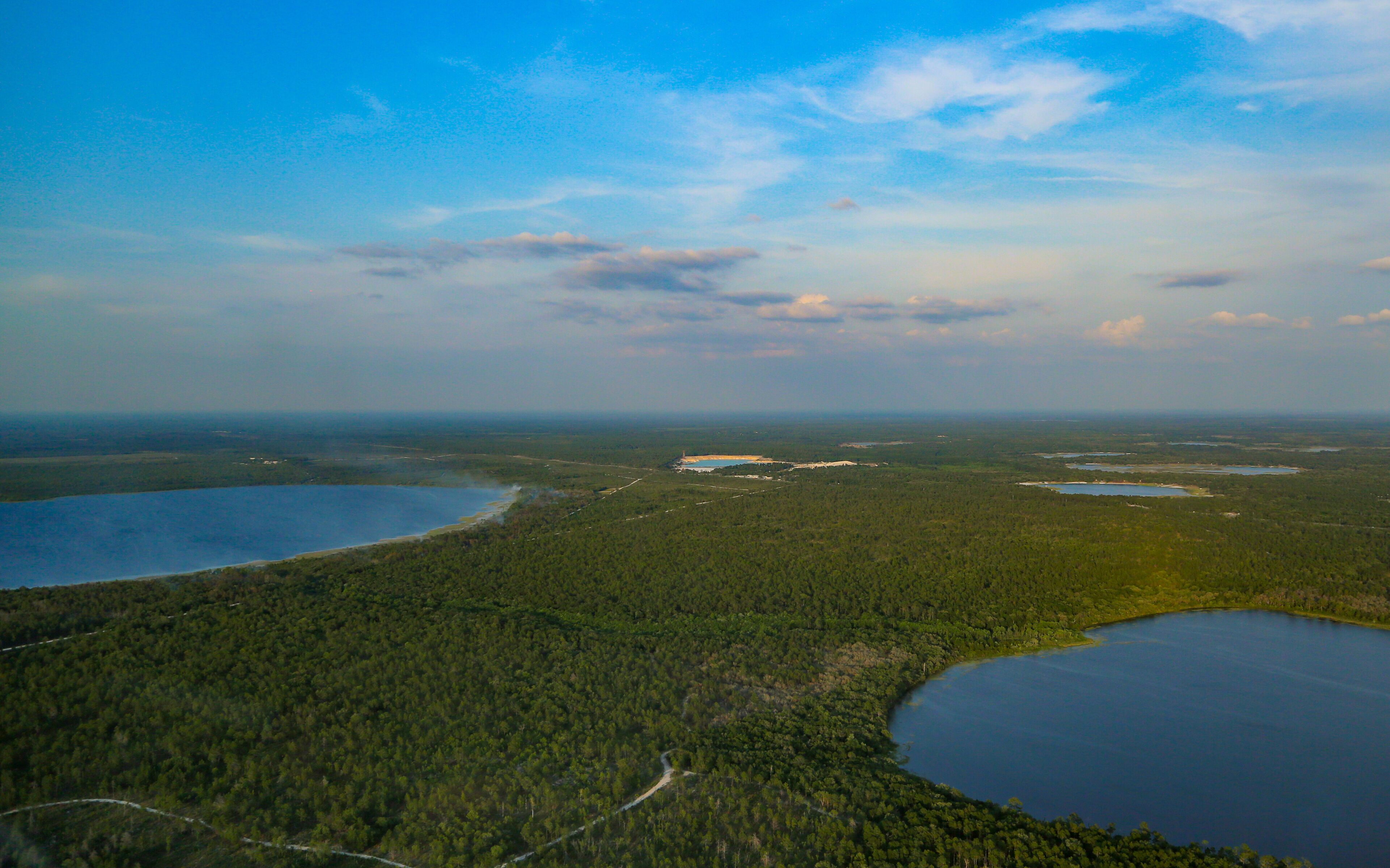 A vast forested landscape with multiple lakes and a clear sky.