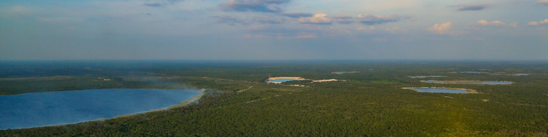 A vast forested landscape with multiple lakes and a clear sky.