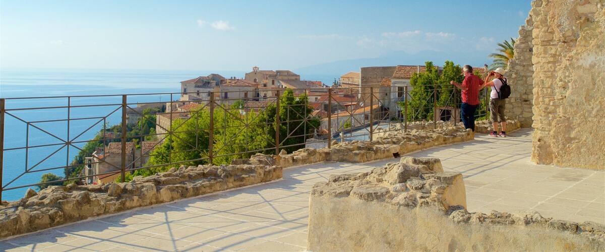 A coastal town with historic buildings, a clear view of the sea, and a stone pathway.