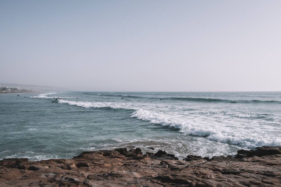 Une côte rocheuse où les vagues se brisent sur la plage.