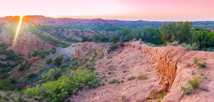 A rugged landscape with a prominent cliff and sparse vegetation.