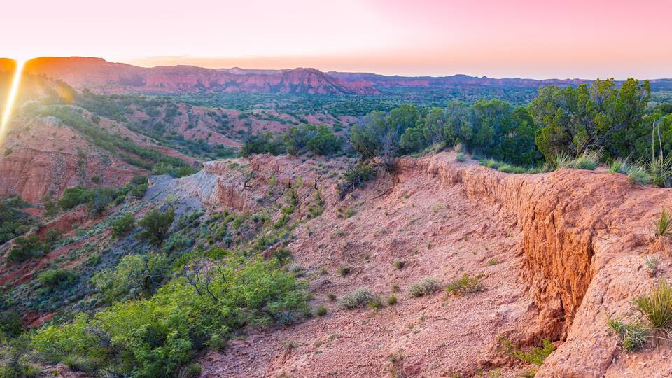 A rugged landscape with a prominent cliff and sparse vegetation.