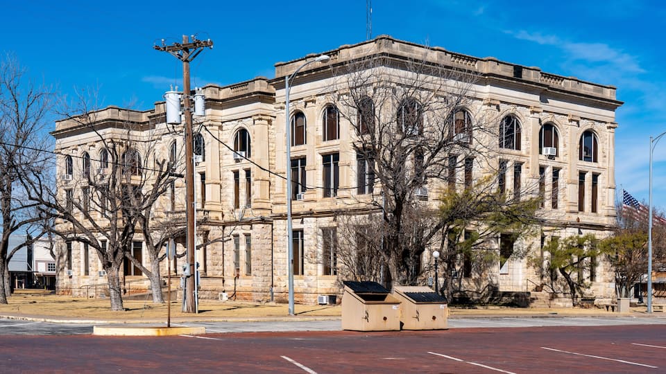 A historic stone building with arched windows and a flag.