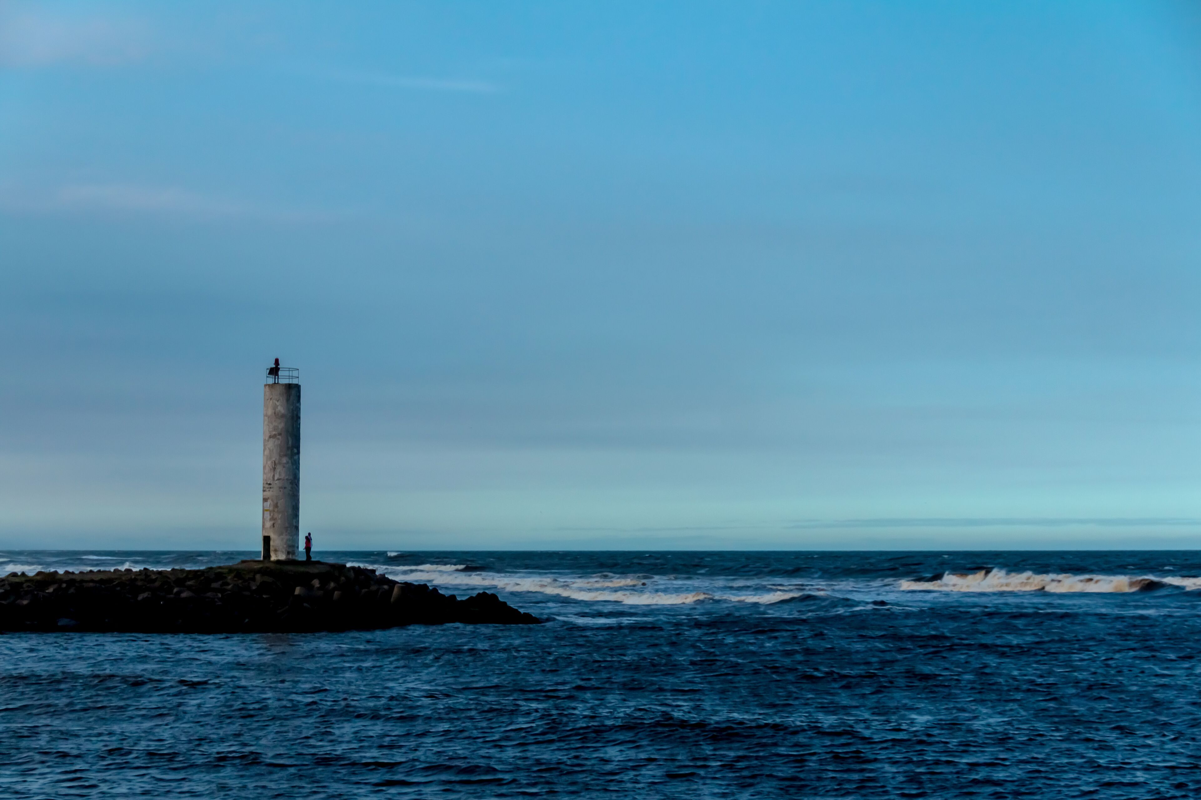 A lighthouse on a rocky outcrop with the ocean in the background.