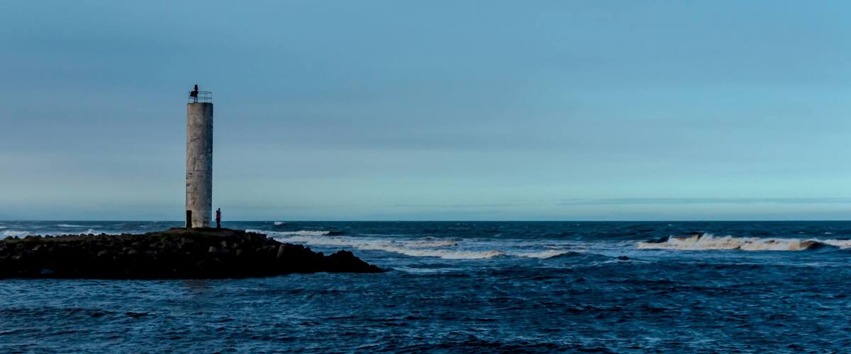 A lighthouse on a rocky outcrop with the ocean in the background.