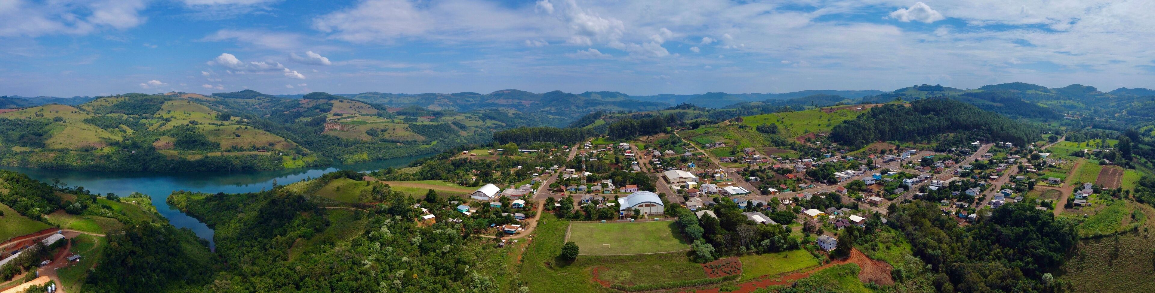 A lush valley with a small town, a lake, and rolling hills.