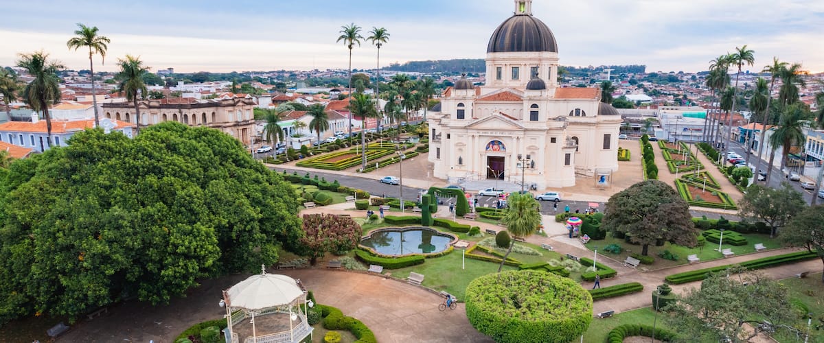 A large church with a dome, surrounded by well-manicured gardens and palm trees.