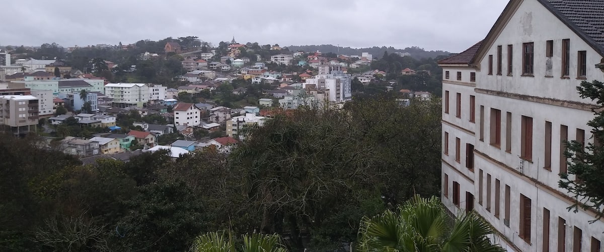 A cityscape with a mix of residential and commercial buildings, surrounded by hills and greenery.