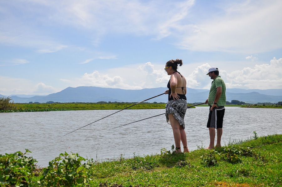 Couple fishing Tres Forquilhas river, next to Itapeva Lagoon. Mountains on background. Capão da Canoa, Rio Grande do Sul, Brazil