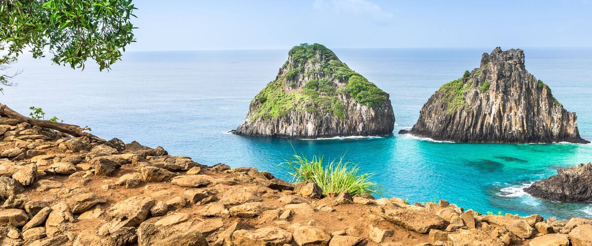 Two rocky islands with lush greenery in turquoise waters.