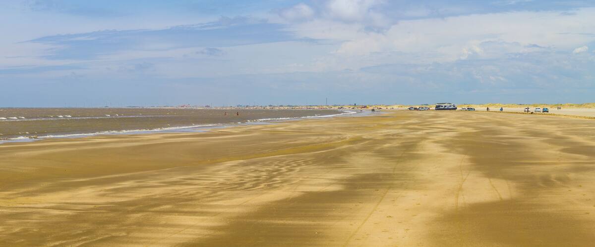 A wide sandy beach with gentle waves and a clear sky.