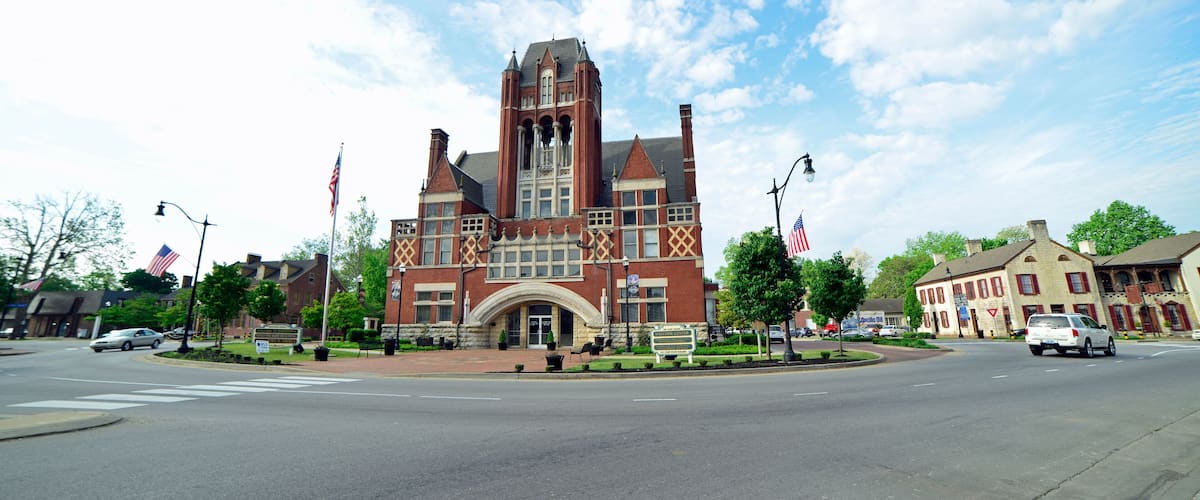 A historic building with a prominent tower, surrounded by a well-maintained lawn and American flags.